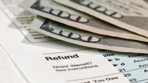 A closeup shot of a stack of three $100 bills sits on top of a document 