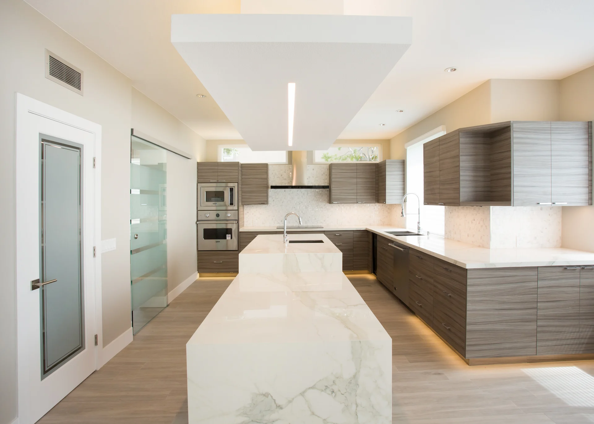 Wide view of the full kitchen over the island, highlighting the spacious layout and contemporary design in the Harbor Cove remodel.