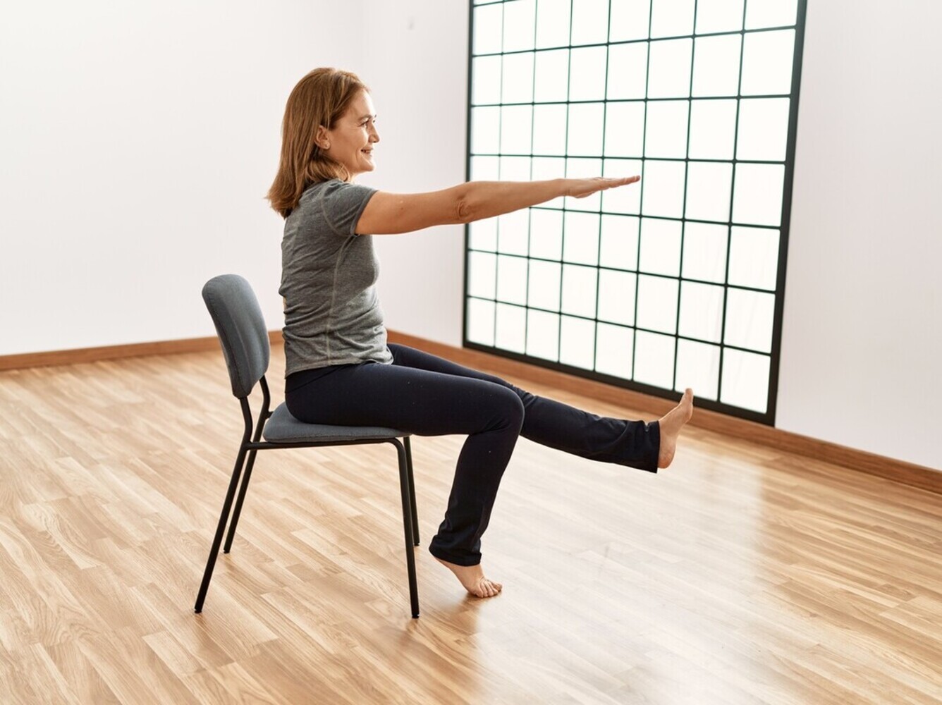middle-aged woman doing leg extension chair exercises for people with limited mobility