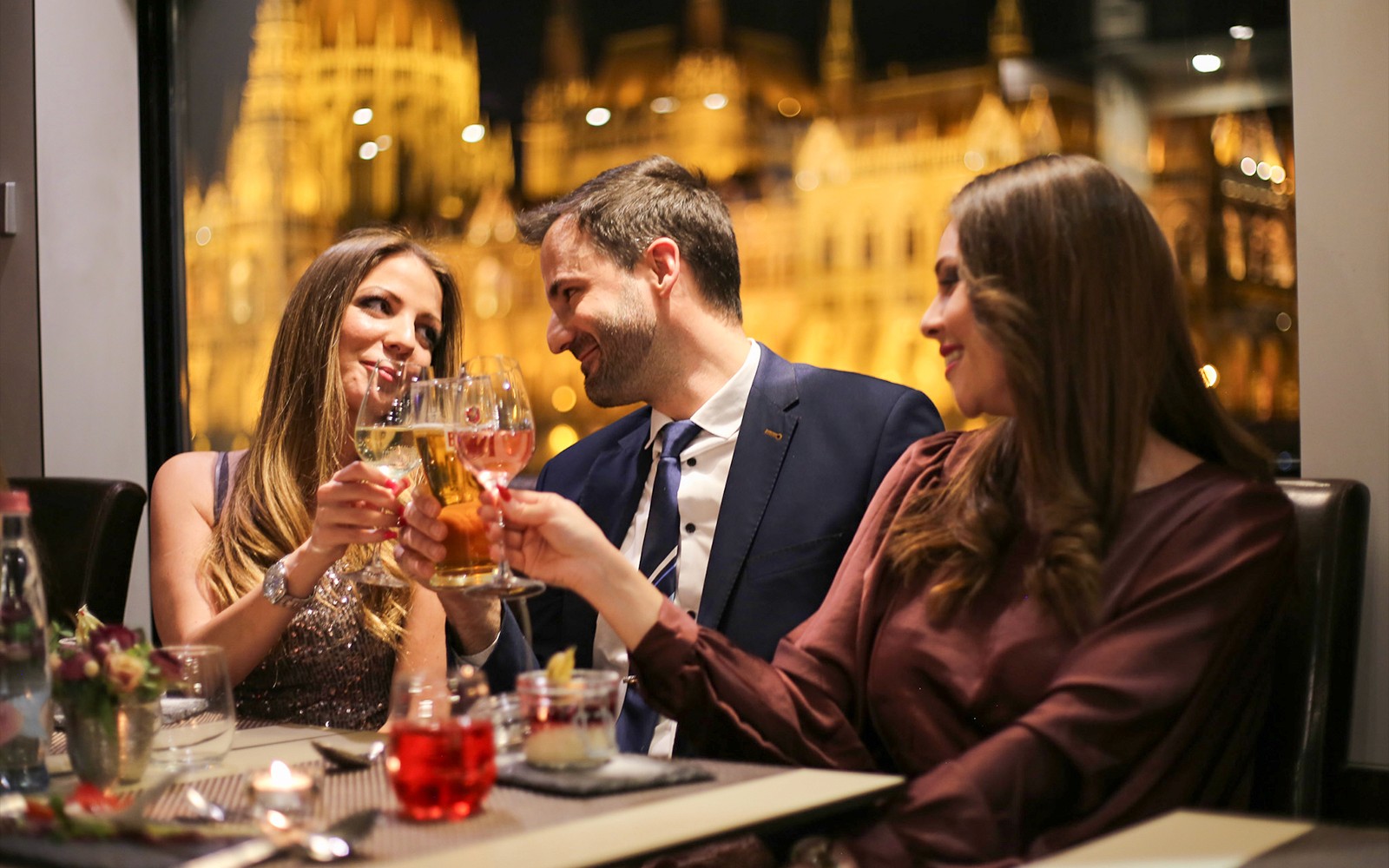 Guests toasting on a Budapest dinner cruise with a piano battle show in the background.