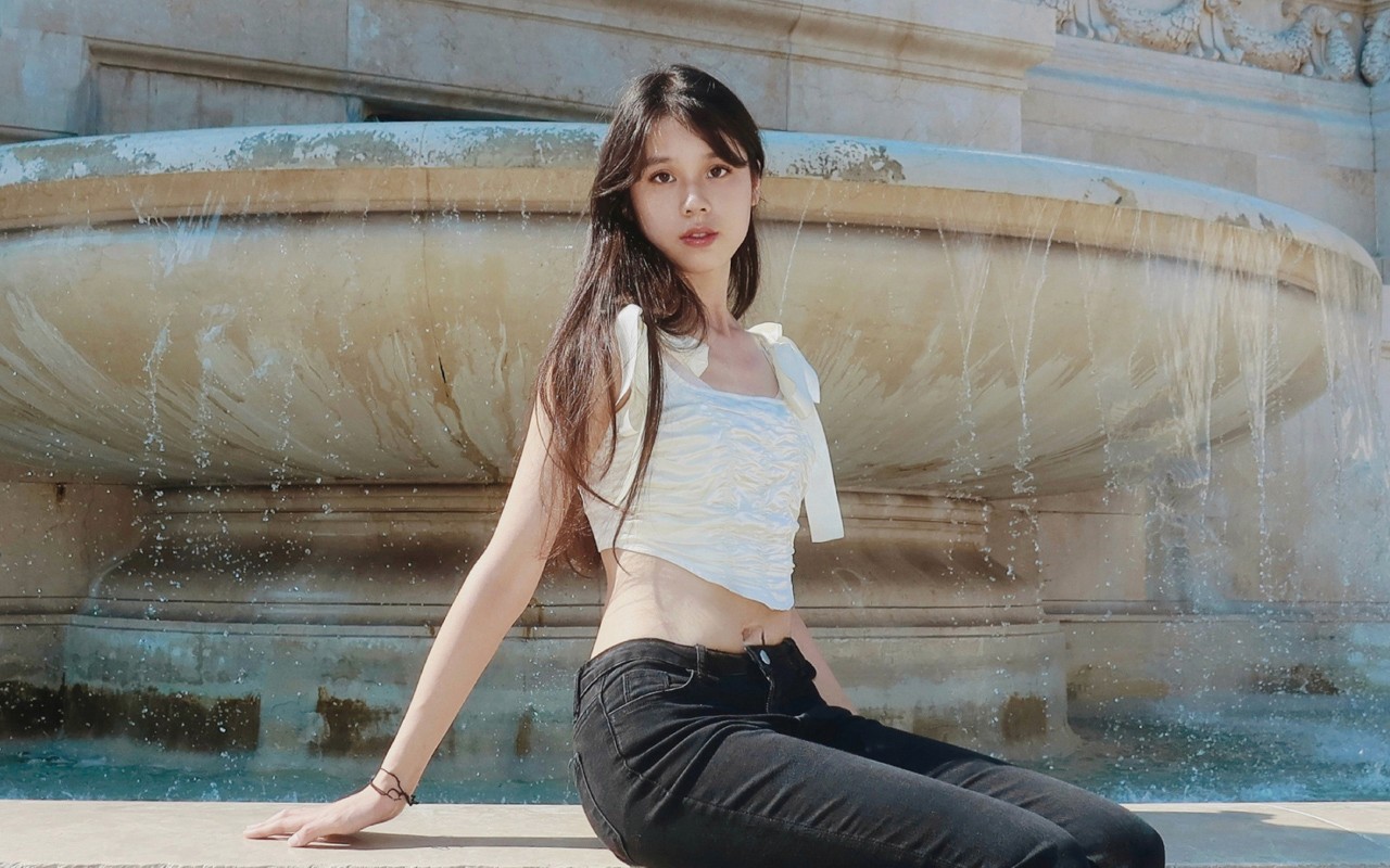 portrait of a woman with long hair in front of a fountain