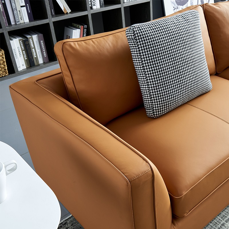 Close-up of burnt orange leather sofa arm with textured black and white houndstooth accent pillow – premium leather upholstery detail