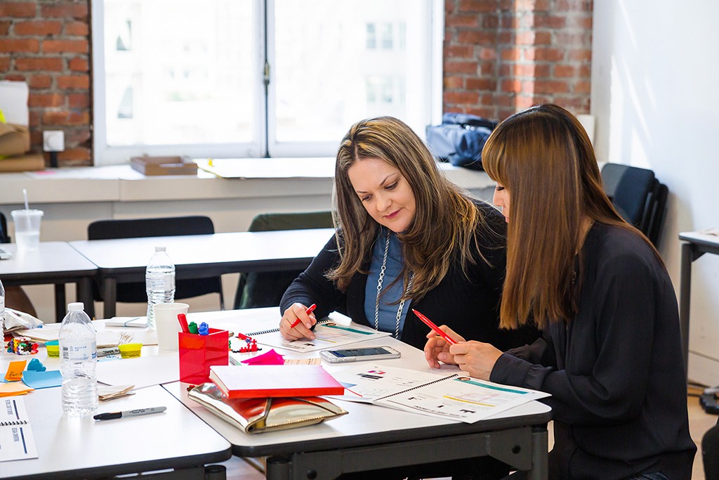 A designer and developer seated side by side, working through a live handoff moment.