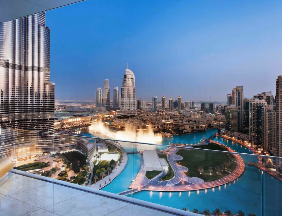 Öffentlicher Platz mit modernen Wolkenkratzern und einer futuristischen Architektur bei Nacht in Dubai.