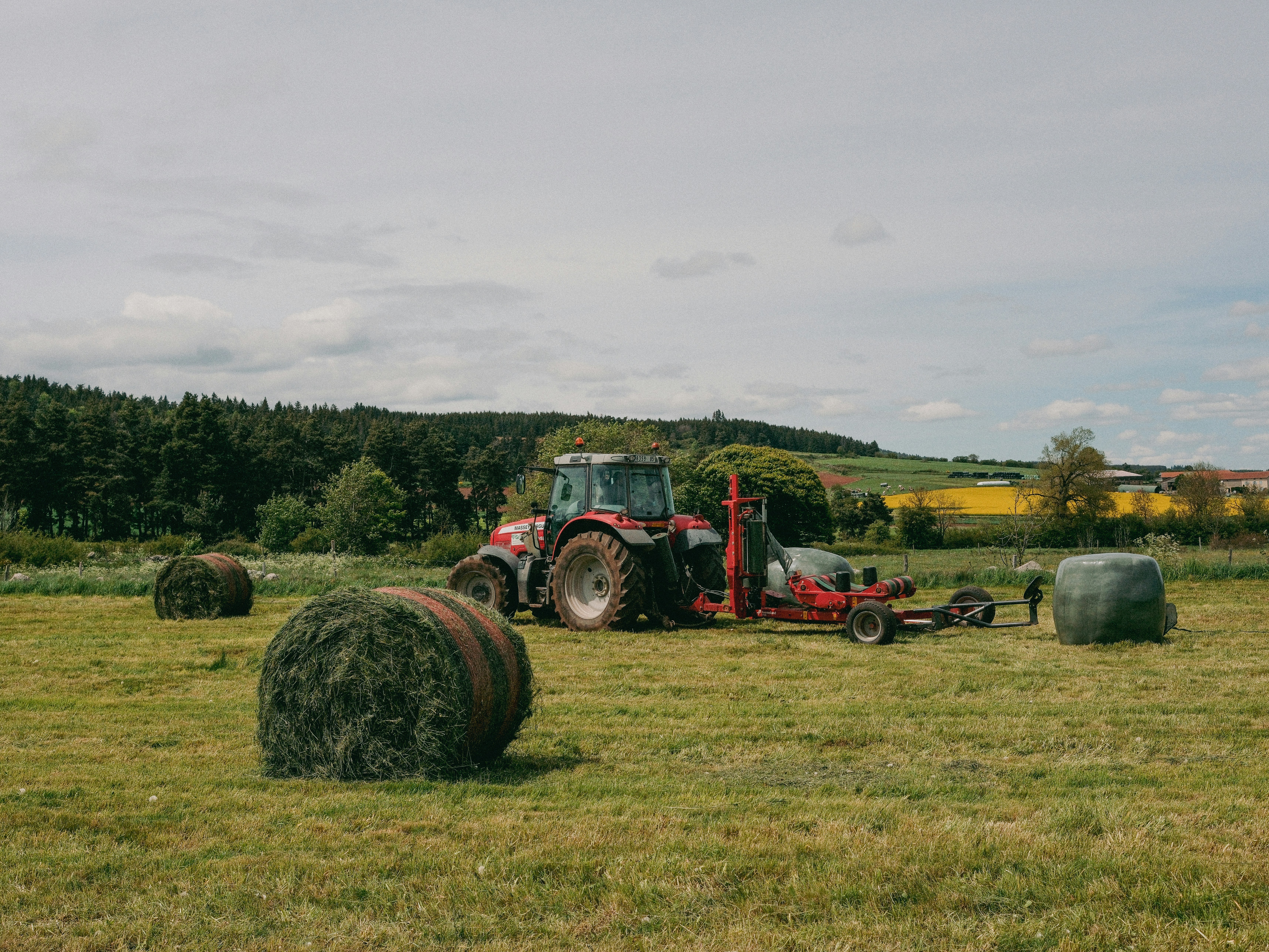 Tractor and round hay bales in a grassy field