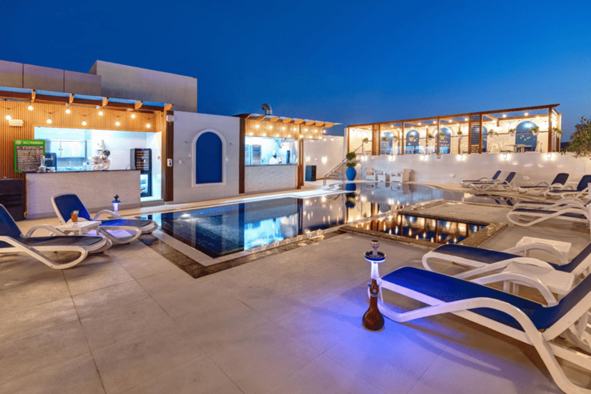 The view of the outdoor pool of the Donatello Hotel, with chairs and an open bar.