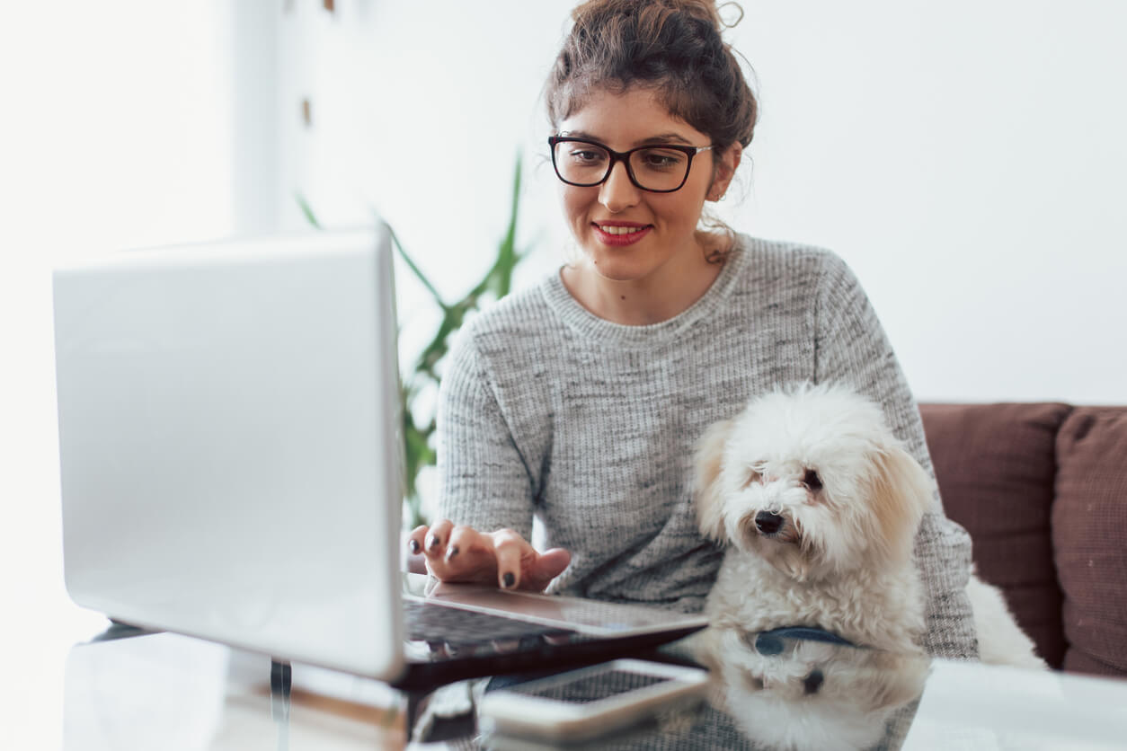 woman on laptop with pet dog at her side