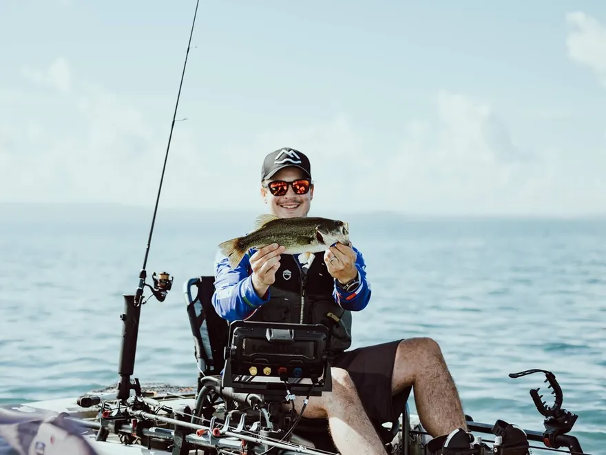 Angler in a fishing kayak holding a fish, Kayakstore case