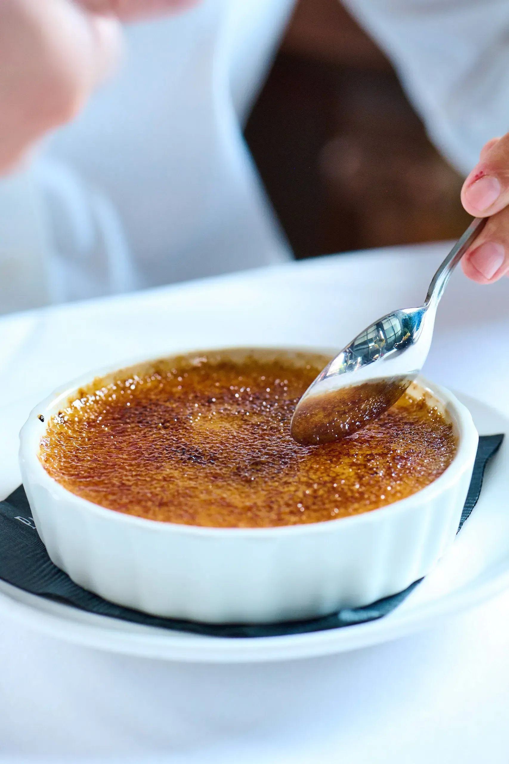 Classic crème brûlée with a caramelized sugar topping being cracked with a spoon.The beer tap and wine/liquer shelf at the red bar
