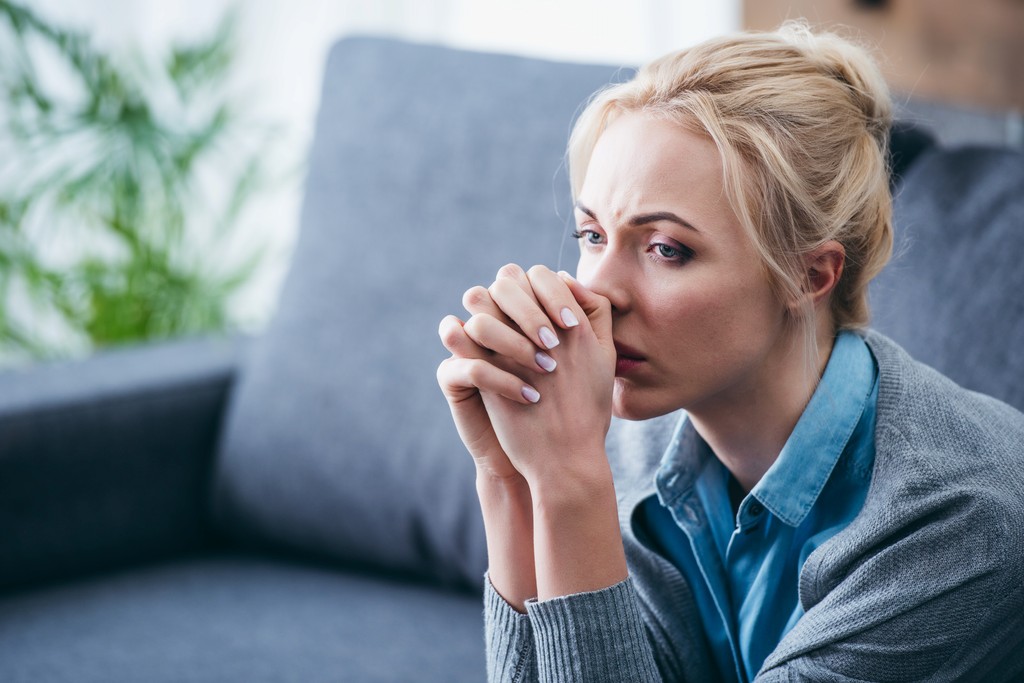 Anxious woman with crossed hands by her face