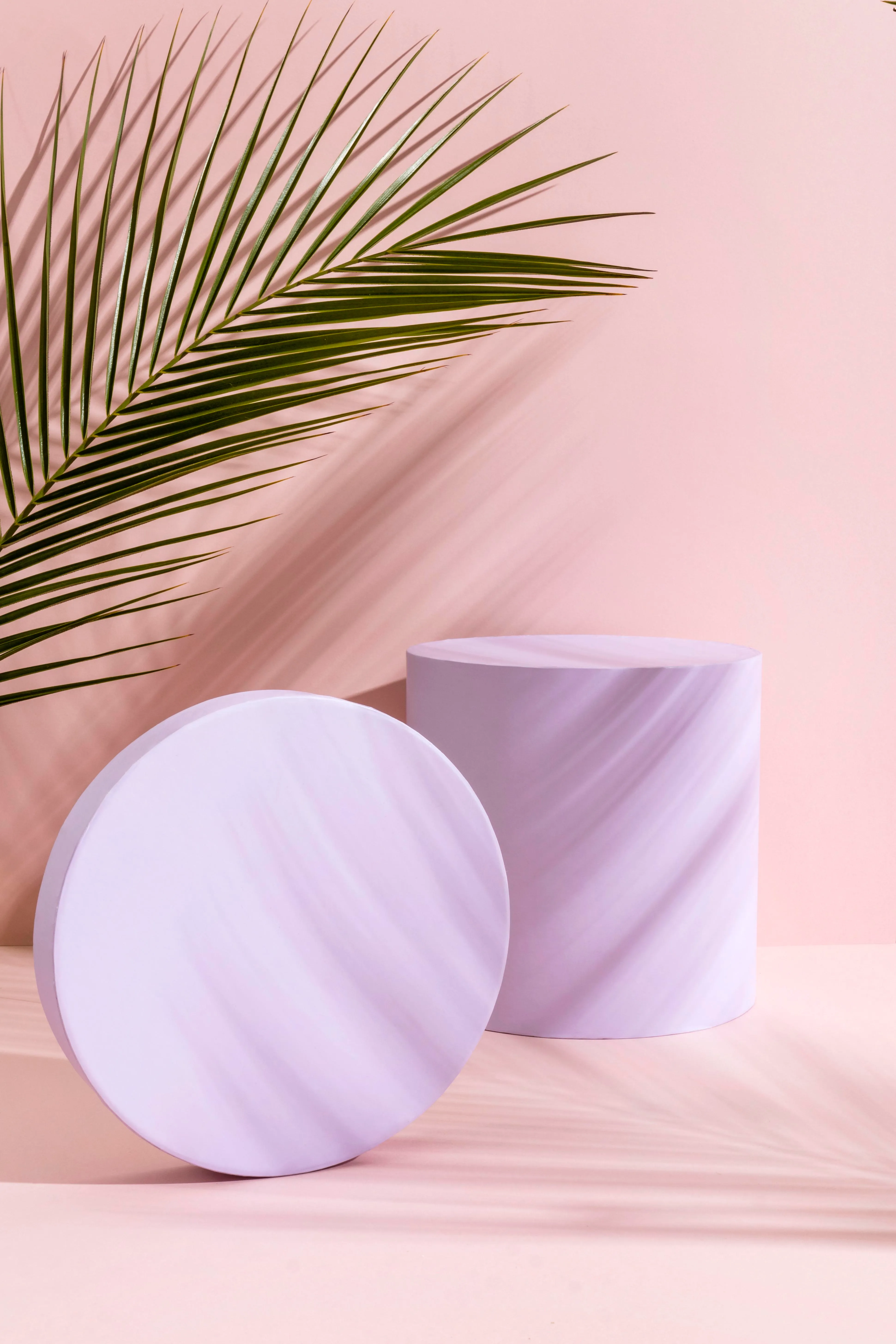 Lilac podiums and a palm leaf on a pink background