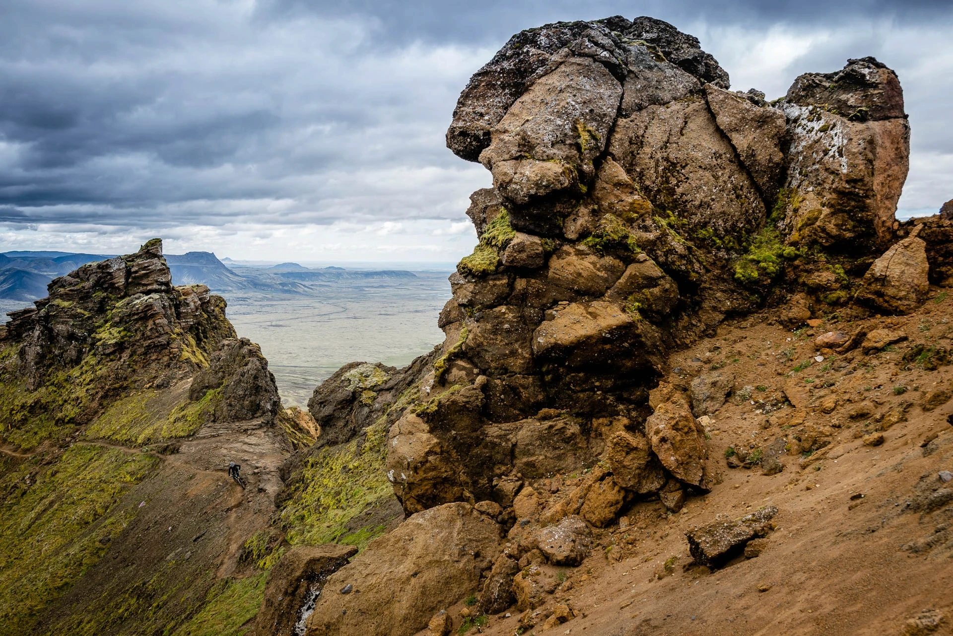 Jagged rock spires above an open valley under a stormy sky.