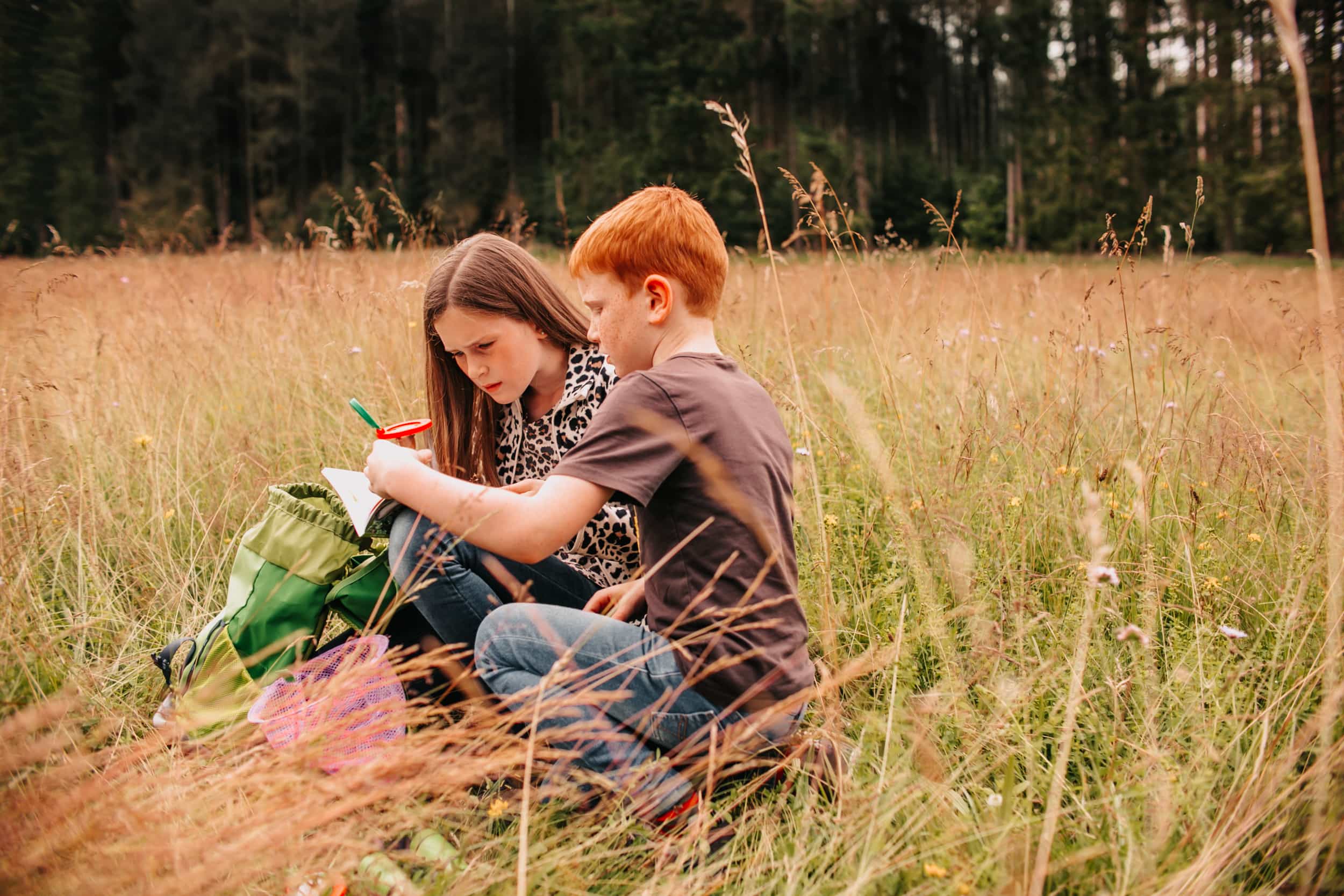 Junge und Mädchen im Gras beim Quiz lösen