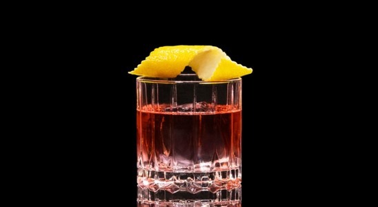 A closeup of a Sazerac drink against a dark background.