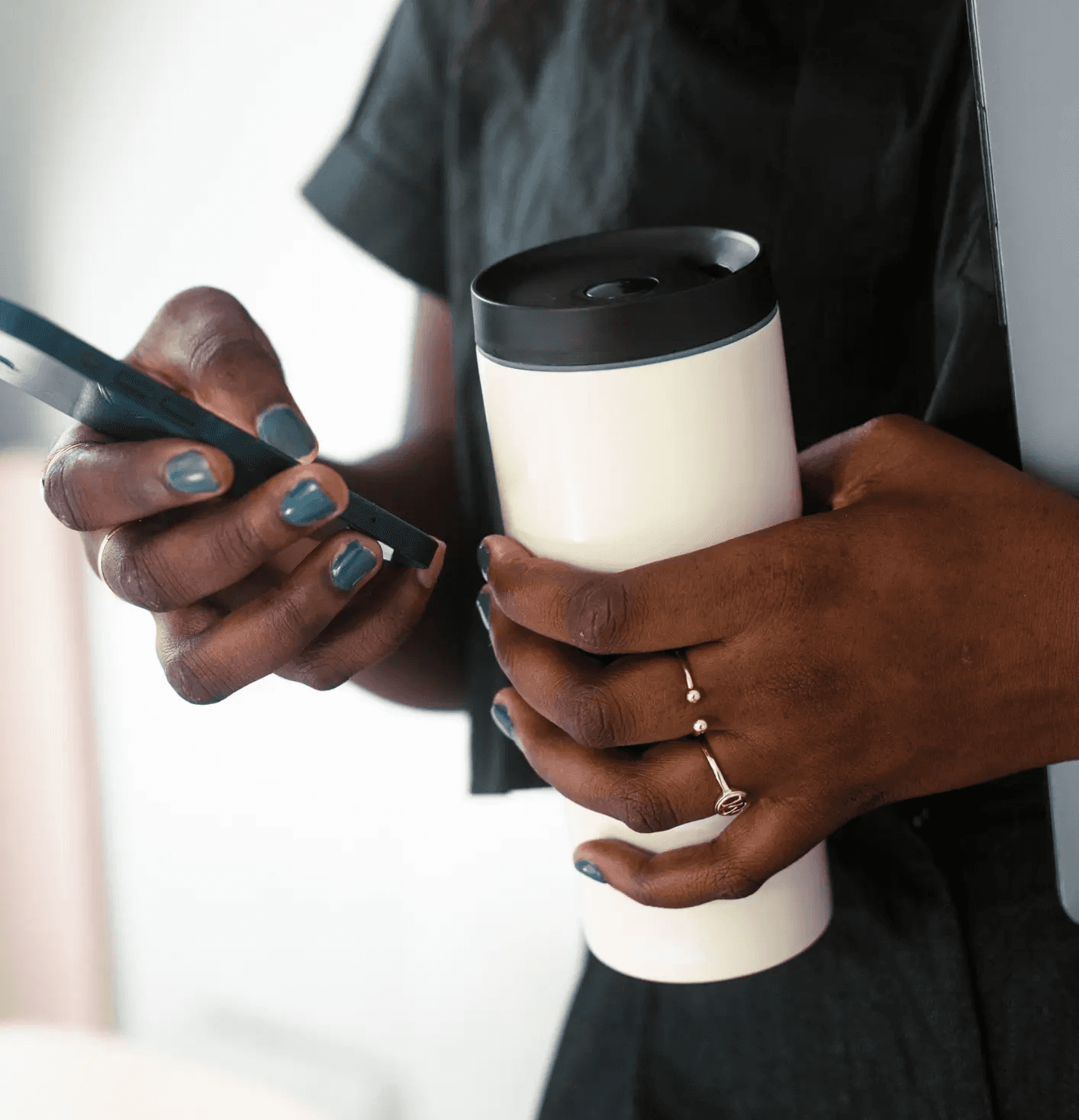 Une personne avec un téléphone dans une main et une gourde dans l'autre.