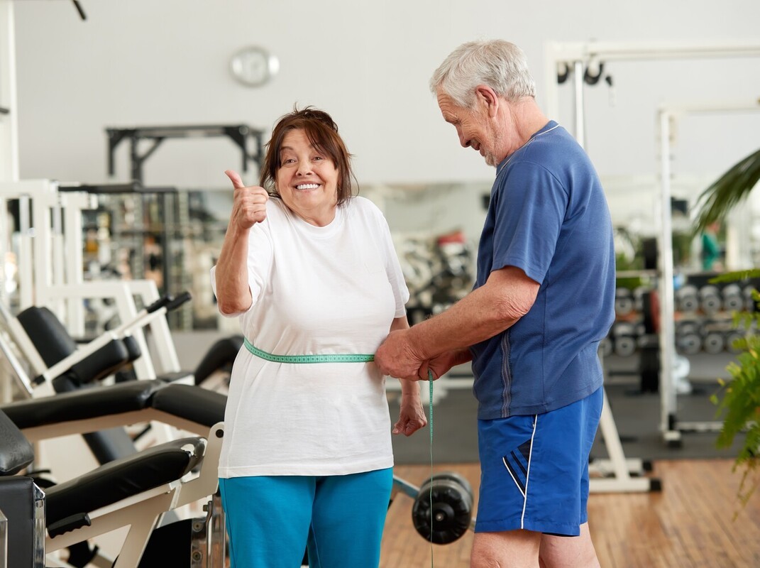 older couple checking their weight loss results with a measuring tape after following the best routine to lose weight