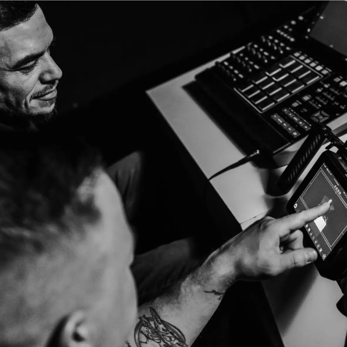 A videographer is presenting a video clip to a music producer.