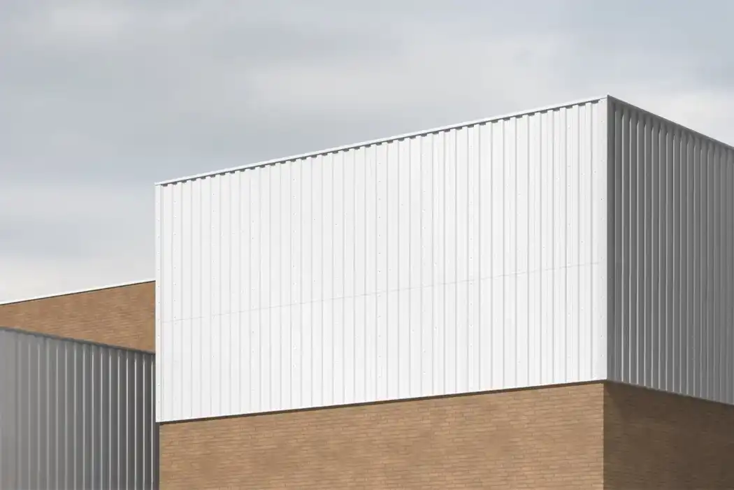 Industrial container mockup with a corrugated metal texture, mounted on a modern brick building. The clean, minimal design is accented by bold typography and a large arrow graphic, set against an overcast sky.