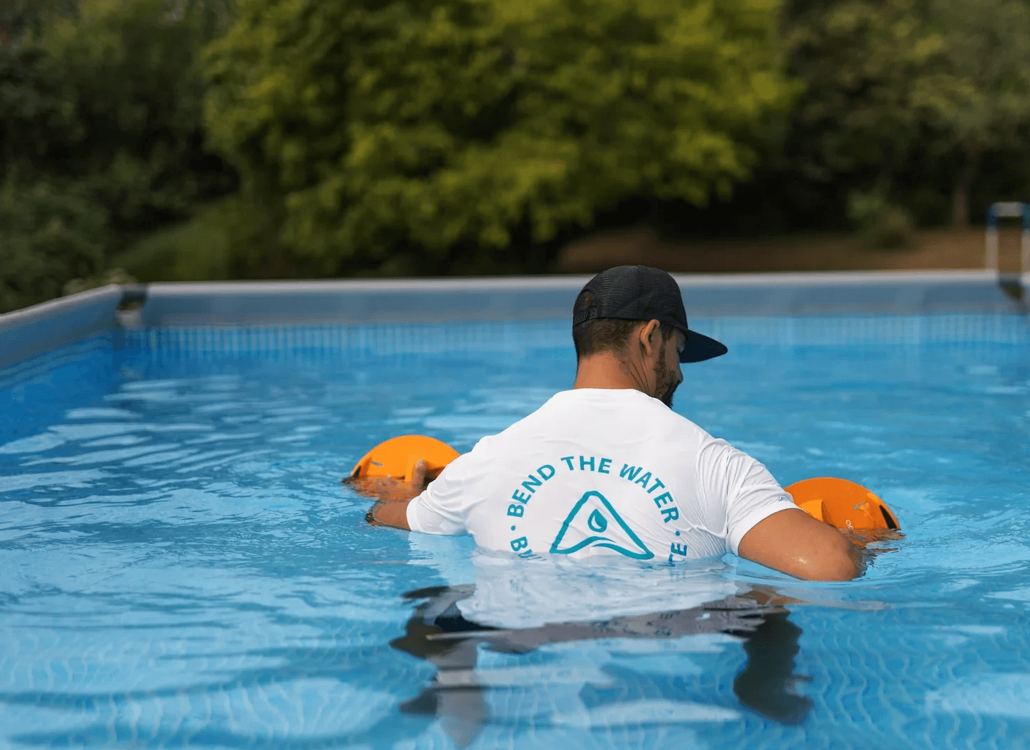 Man in pool performing back pull exercise with Aqua-Bend disc, back muscles engaged