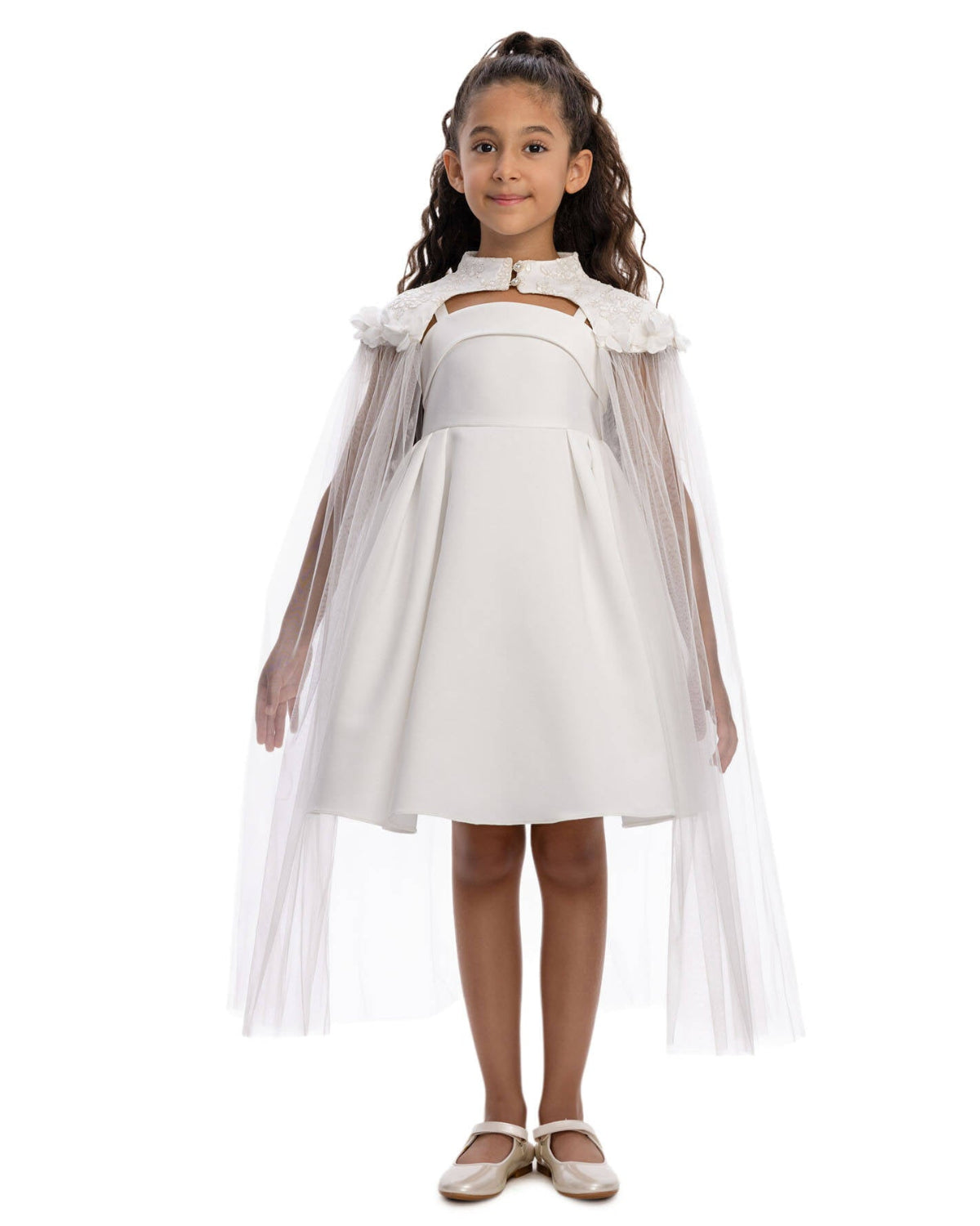 Young girl wearing a white dress with a sheer overlay on a white background