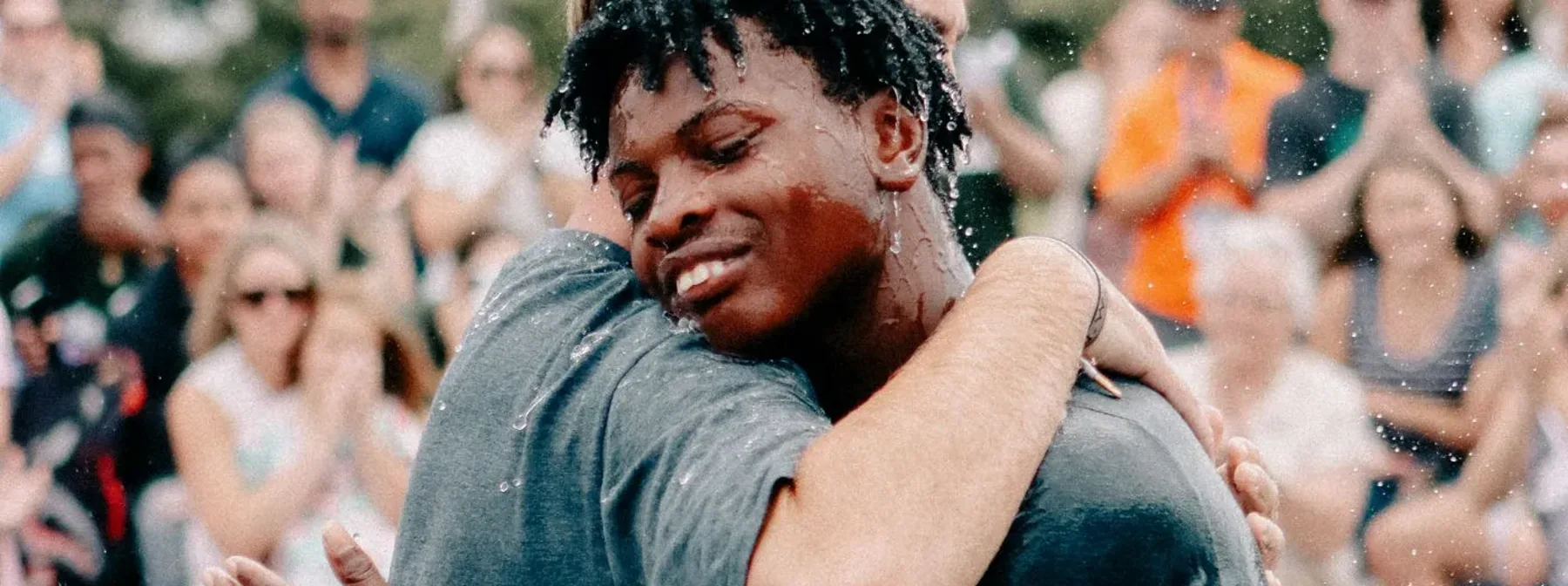 Two friends hugging in the water after a baptism