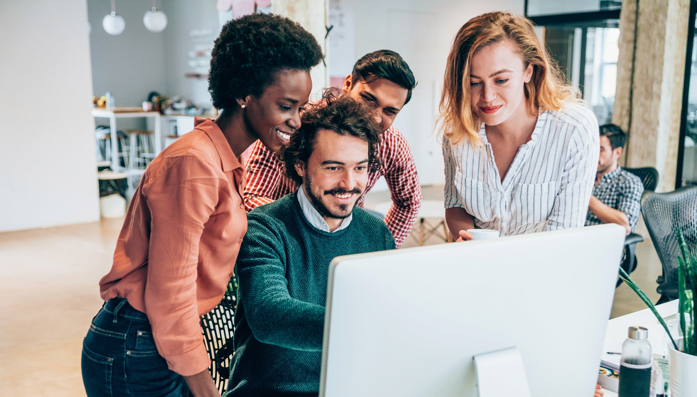 Two women and a man looking animatedly at a screen in an office