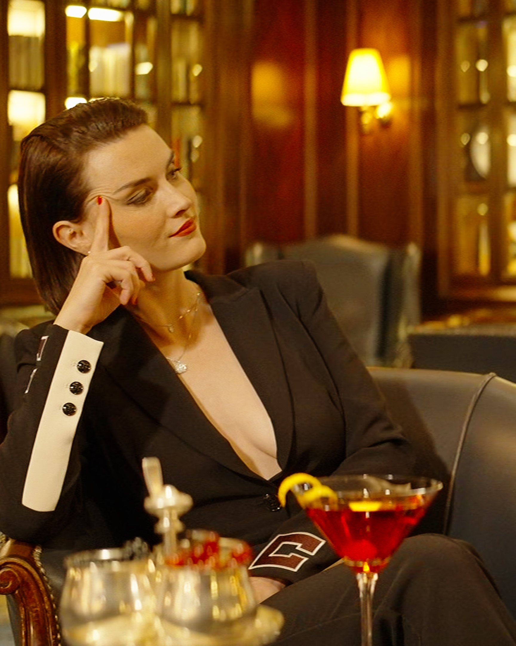 Model sitting in the bar of an hotel with a cocktail in front of her