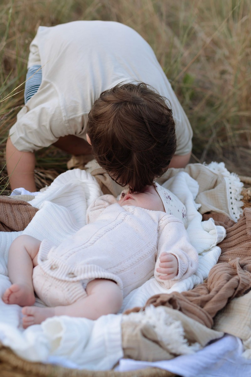 sibling kissing newborn baby in a newborn session in Mackay