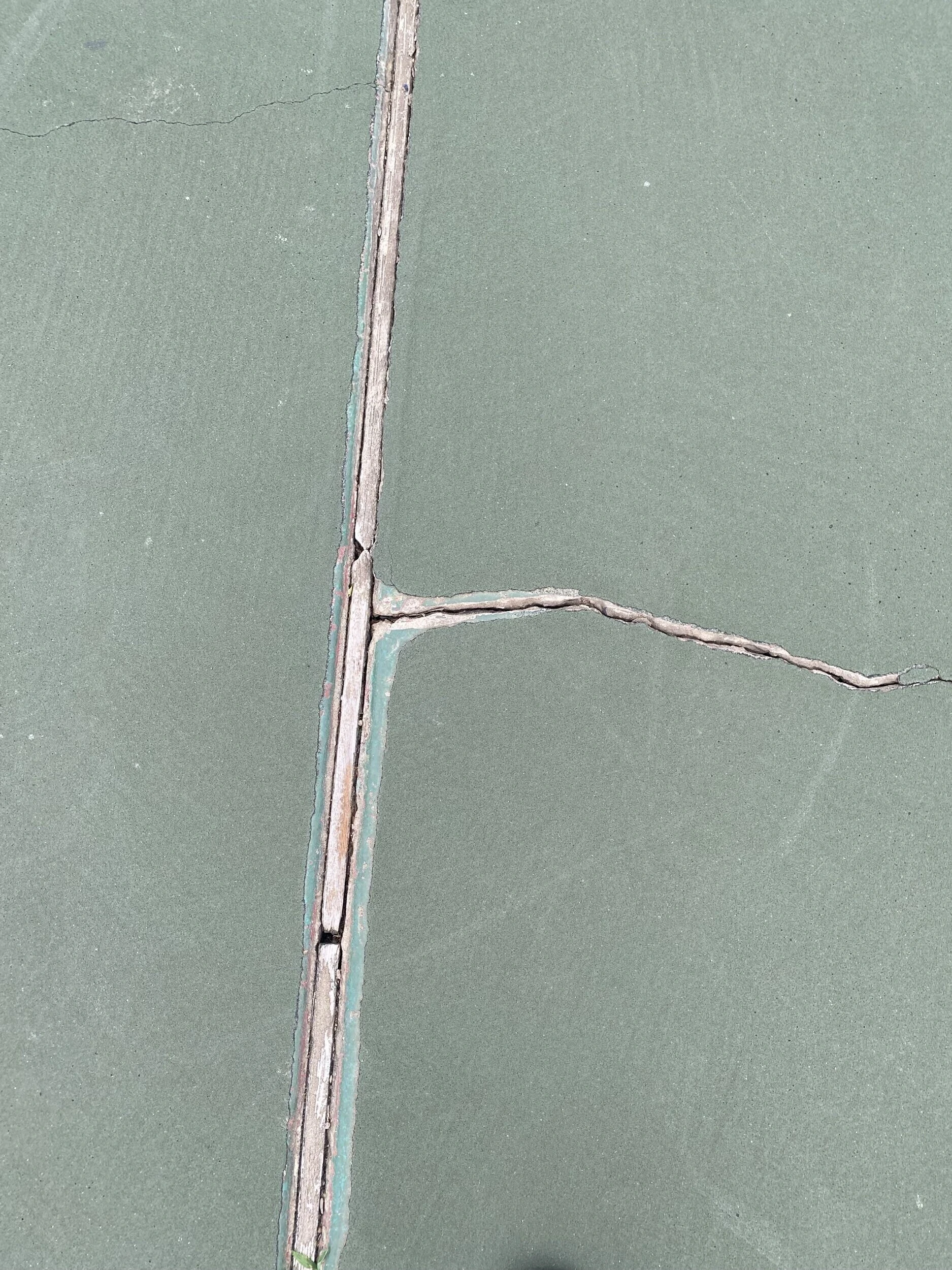 Weathered expansion joint and branching surface cracks on worn court at Bell Park in Greenwood, AR