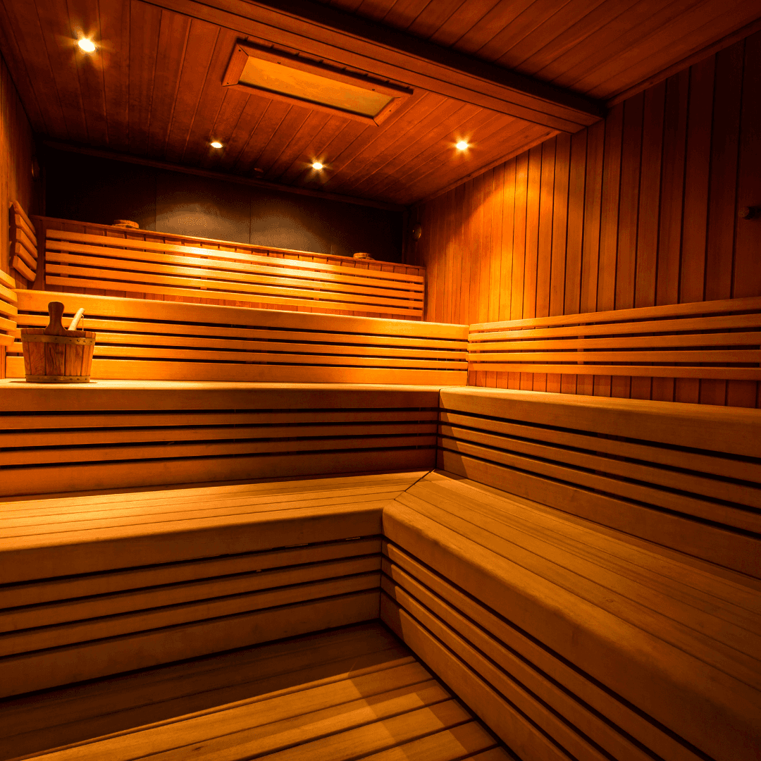 A modern green chair with a curved design and dark wooden legs against a dark background.