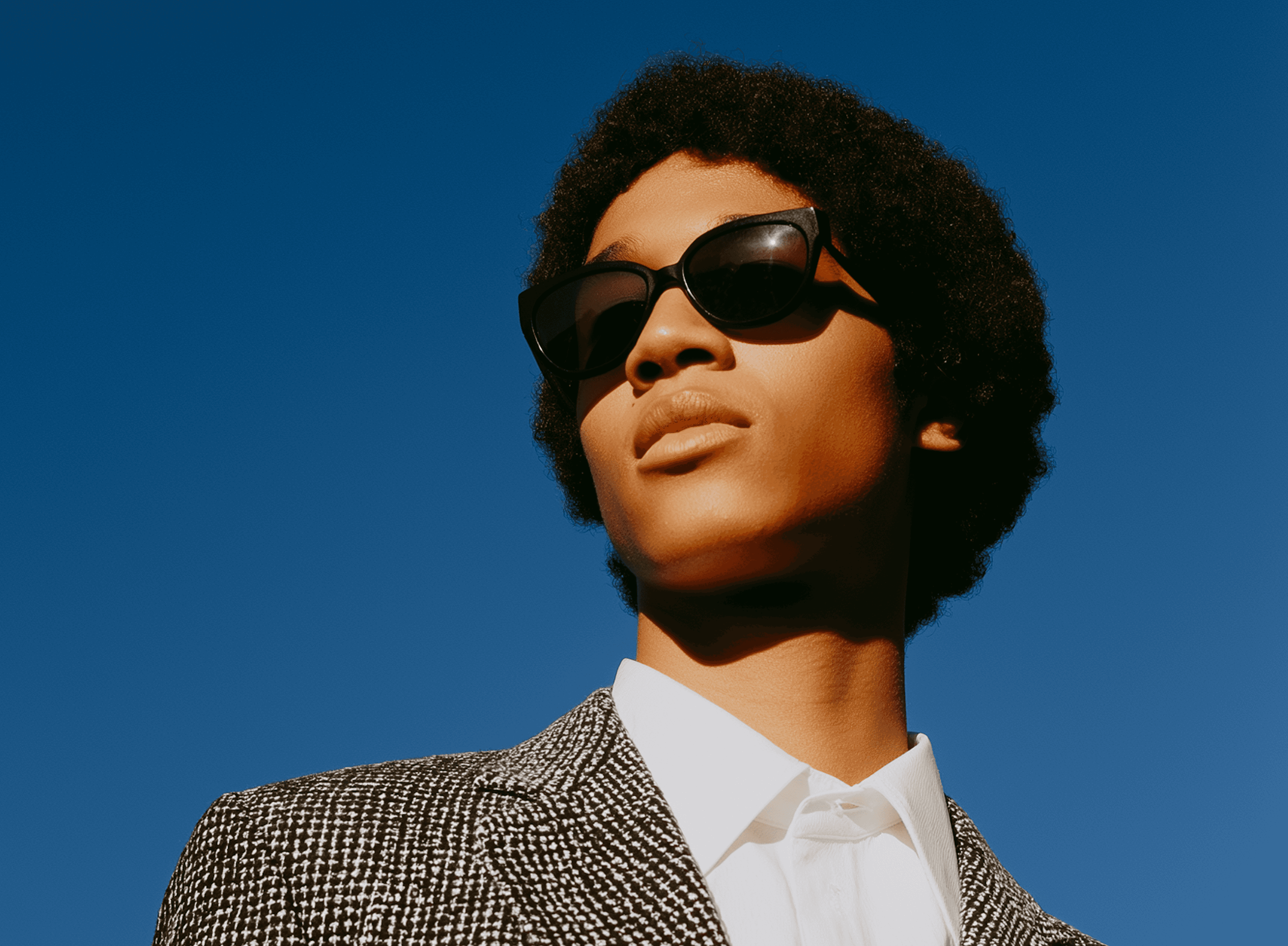 Person in sunglasses against a blue sky.