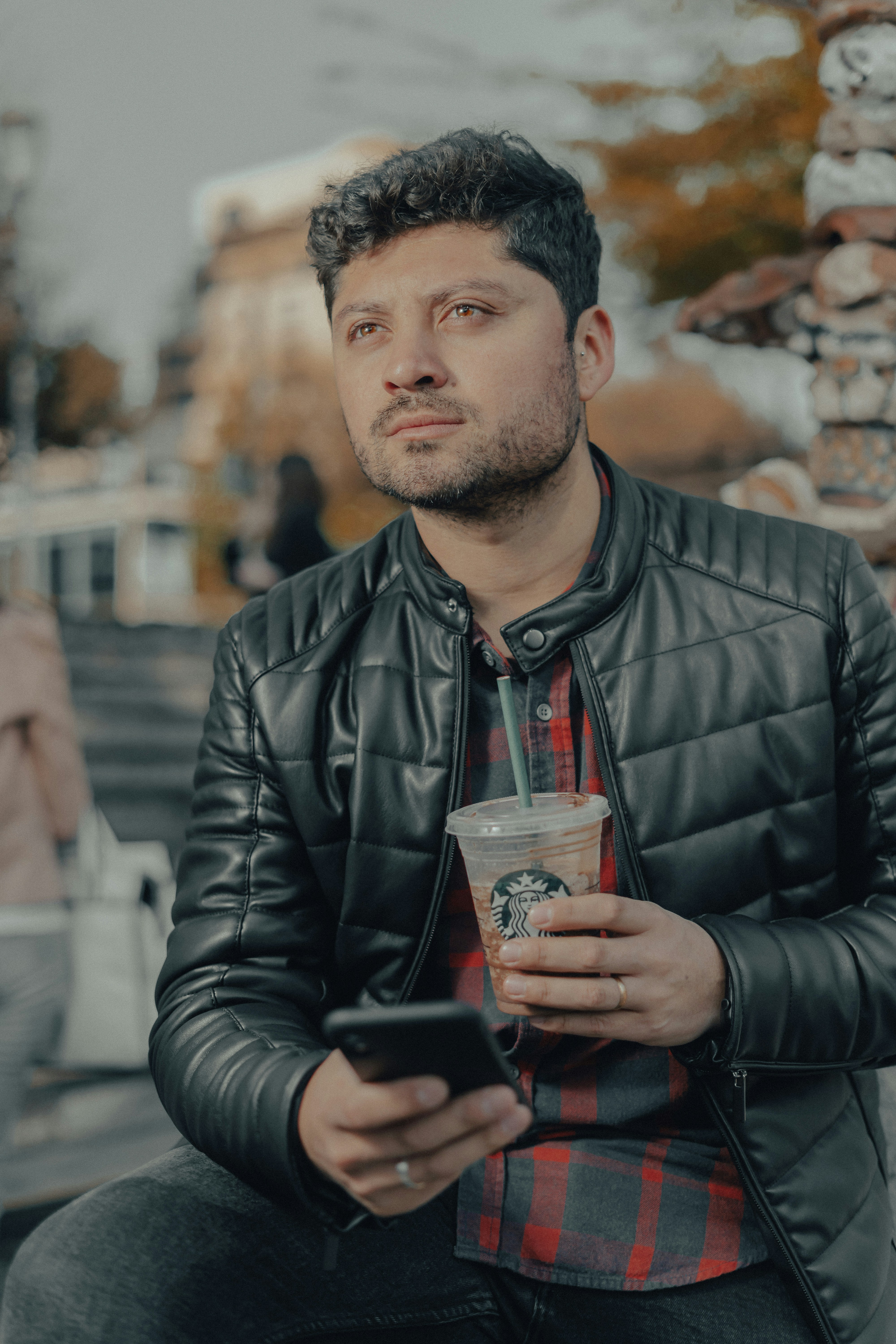 man in black leather jacket holding clear drinking glass