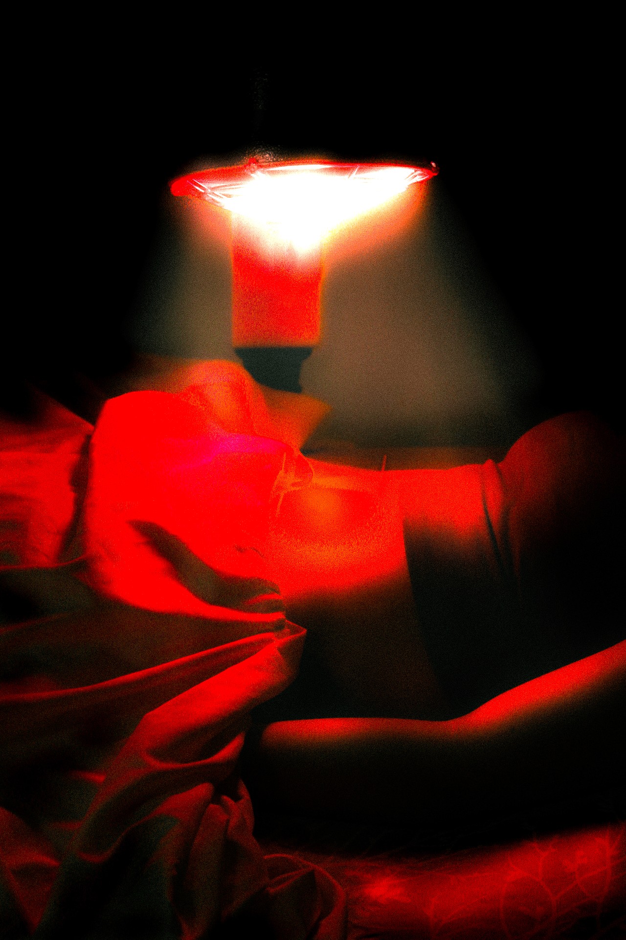 An individual laying down with red light therapy being used over their stomach area