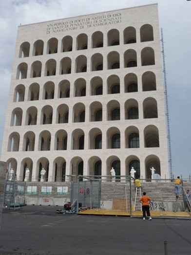 A photo of a renovated multistore ancient building with arches on each level and a few white stone sculptures below.