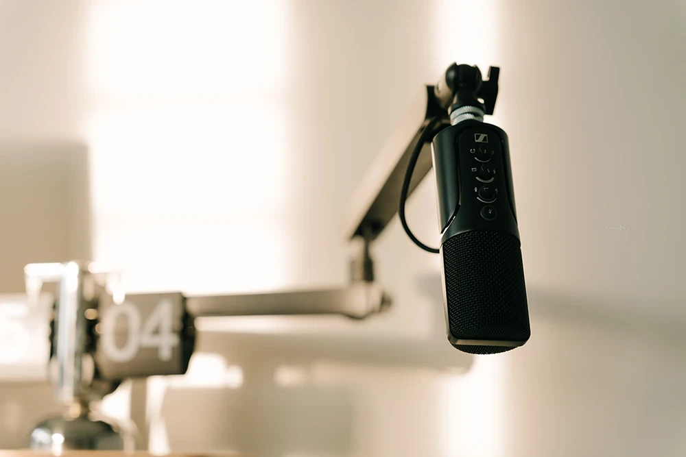 A podcast mic suspended from a stand in a podcast room