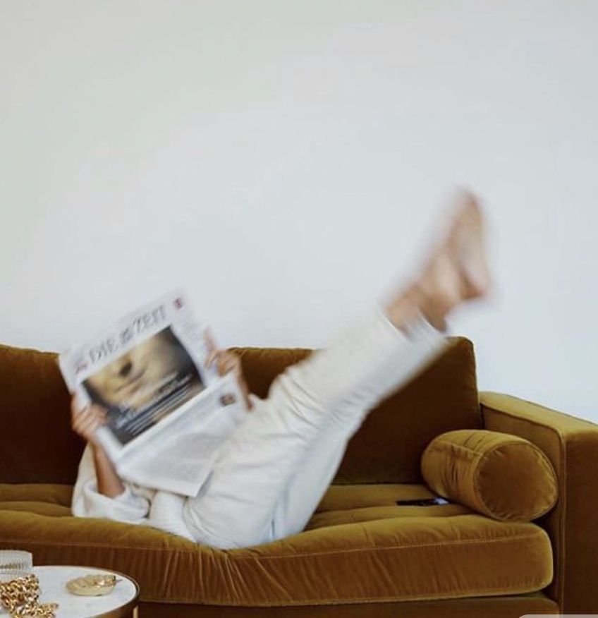 Restaurant interior with wooden tables and chairs lined against a textured wall, softly lit by round wall lamps.