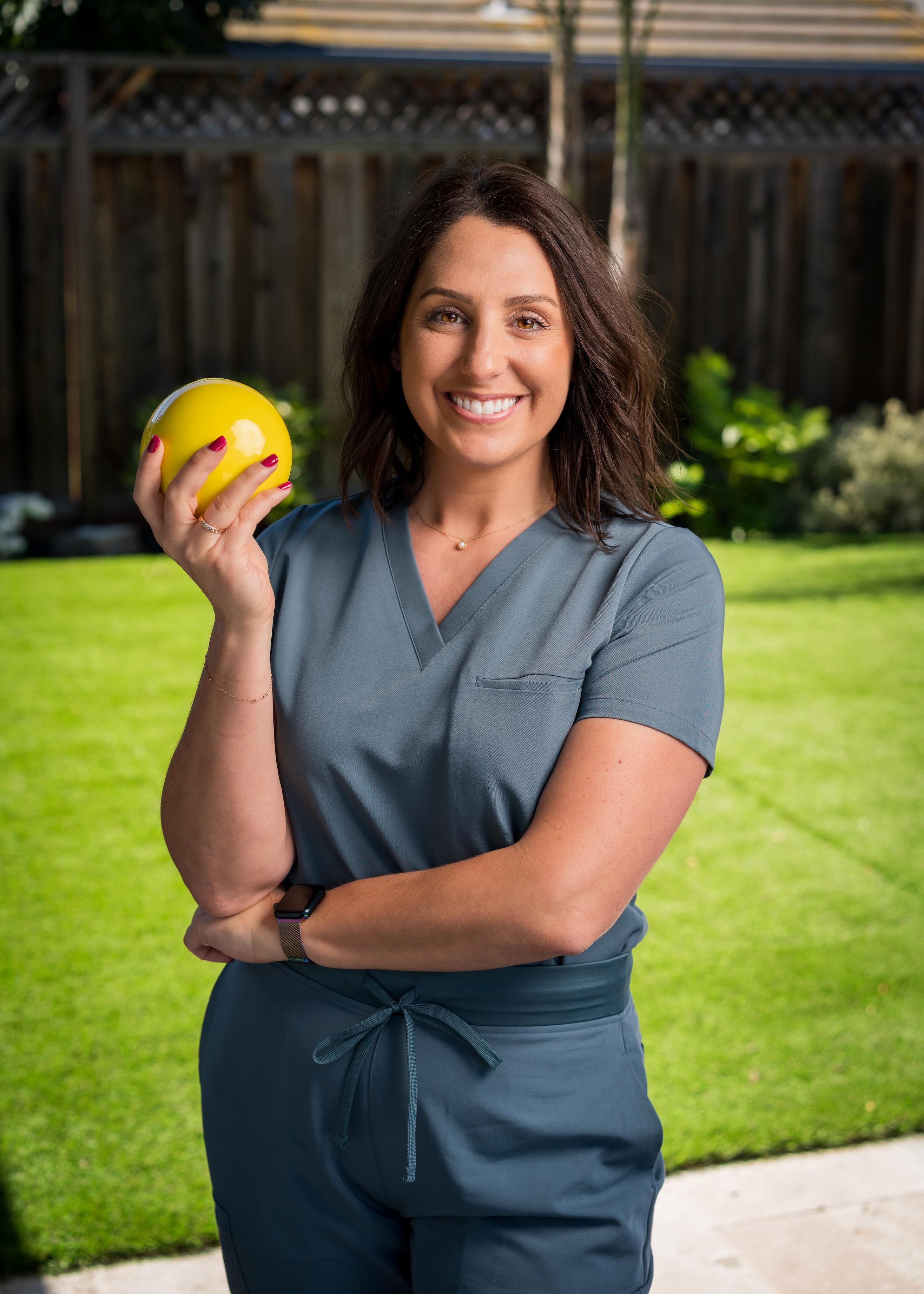 Iamge of Valerie Vargas, Occupational Therapist, and owner of The Hand Collective holding a weighted therapy ball