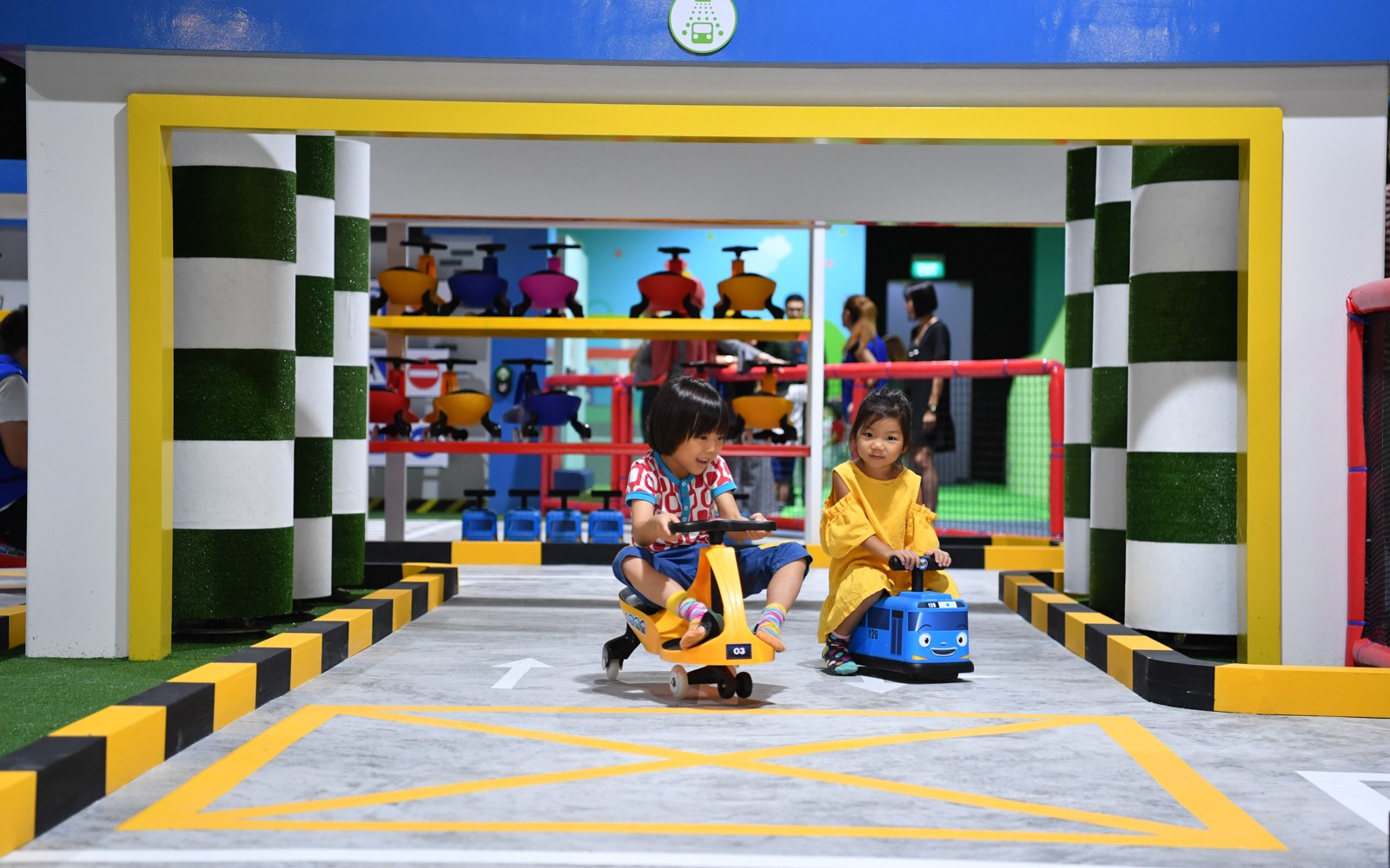 Children riding toy vehicles at Tayo Station indoor playground.