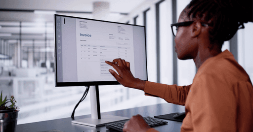 Person pointing at a computer screen while making business finance decisions in the office.