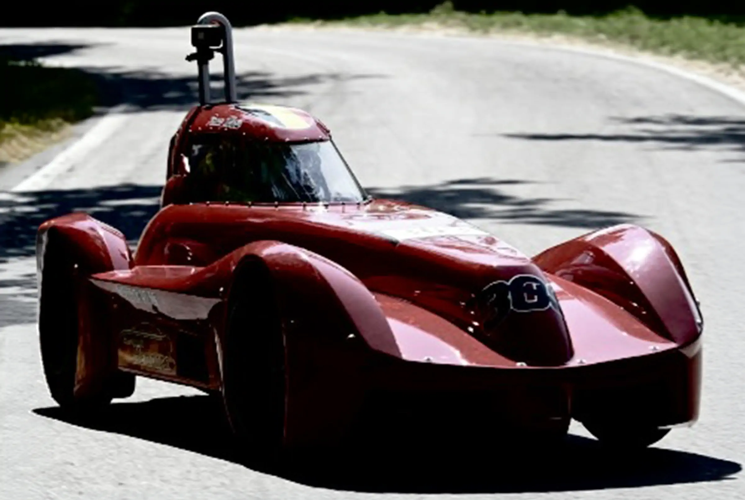 Caisse à savon rouge bordeaux en pleine descente sur la route, GoPro embarquée