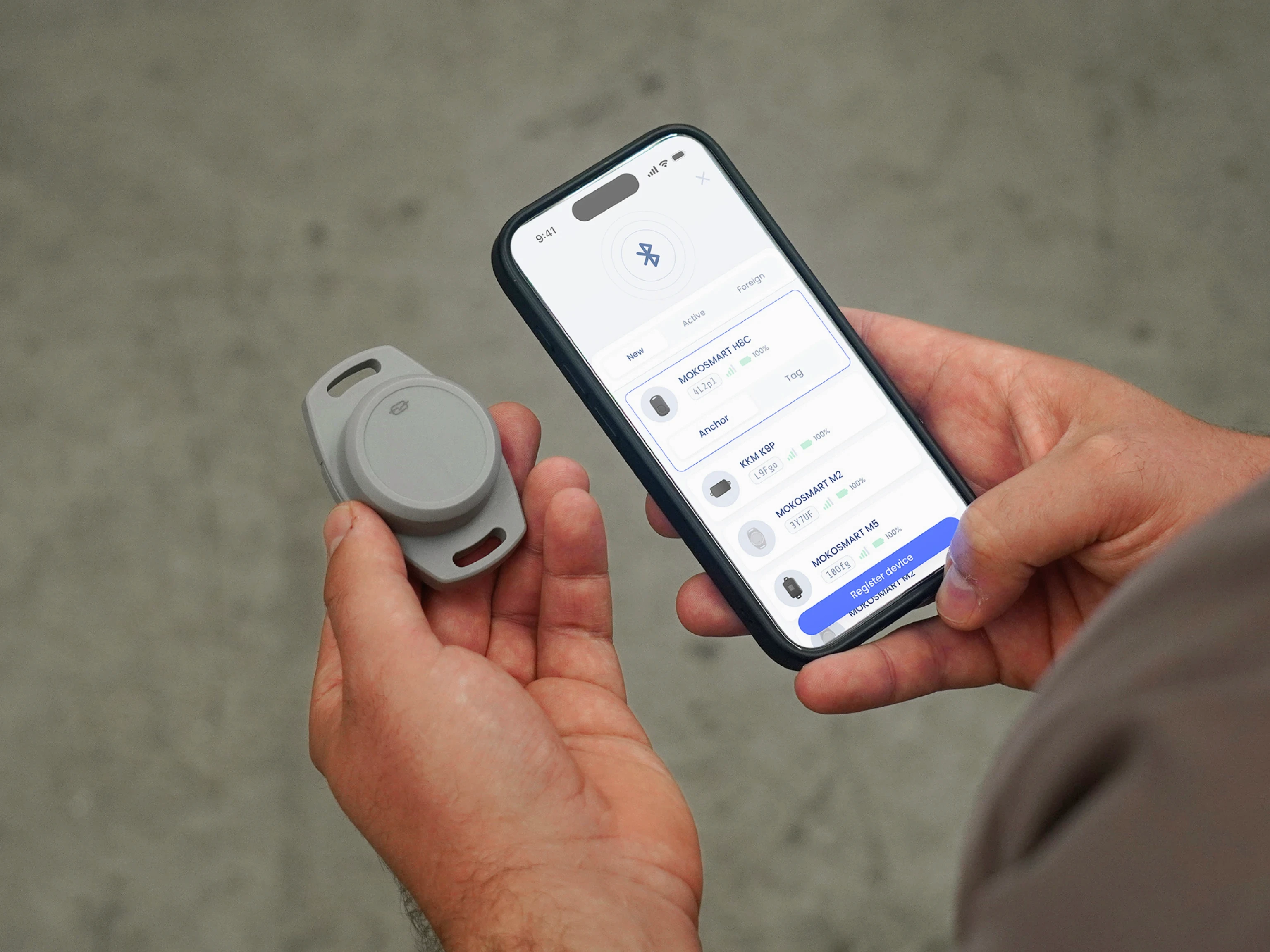 Person holding Mokosmart L03 tracker next to Velavu mobile app during setup