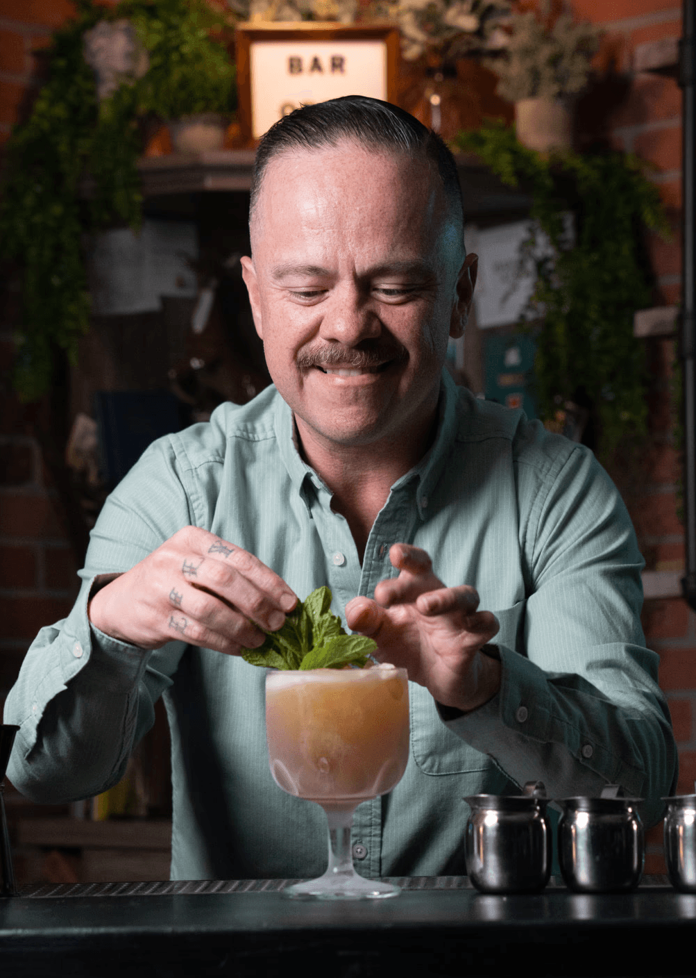 Erick Castro, Bartender at Large, garnishing a cocktail behind the bar.