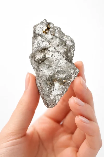 isolated hand holding a silver rock resembling MAGNESIUM on a white background.