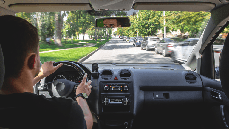 Kierowca patrzy na drogę przez przednią szybę samochodu podczas jazdy po mieście.