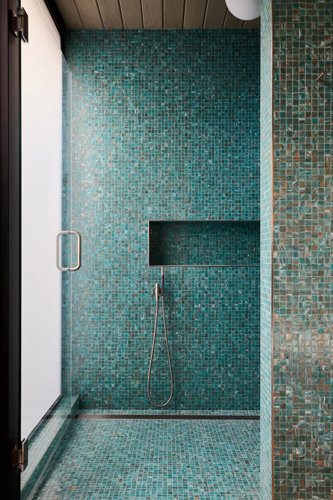 Portrait of the master shower featuring a linear drain, combining modern functionality with elegant design in this Eichler home. Photo by Todd Huge.