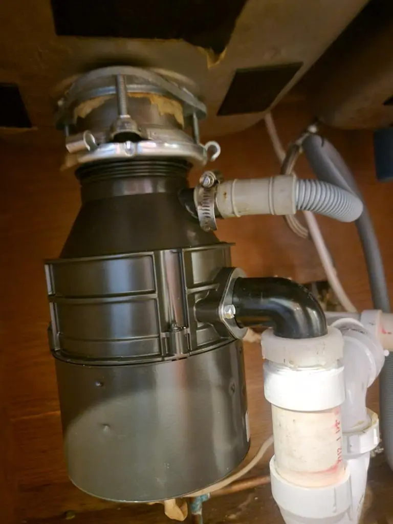 A close-up view of a garbage disposal unit's sink flange and mounting assembly during a garbage disposal repair.