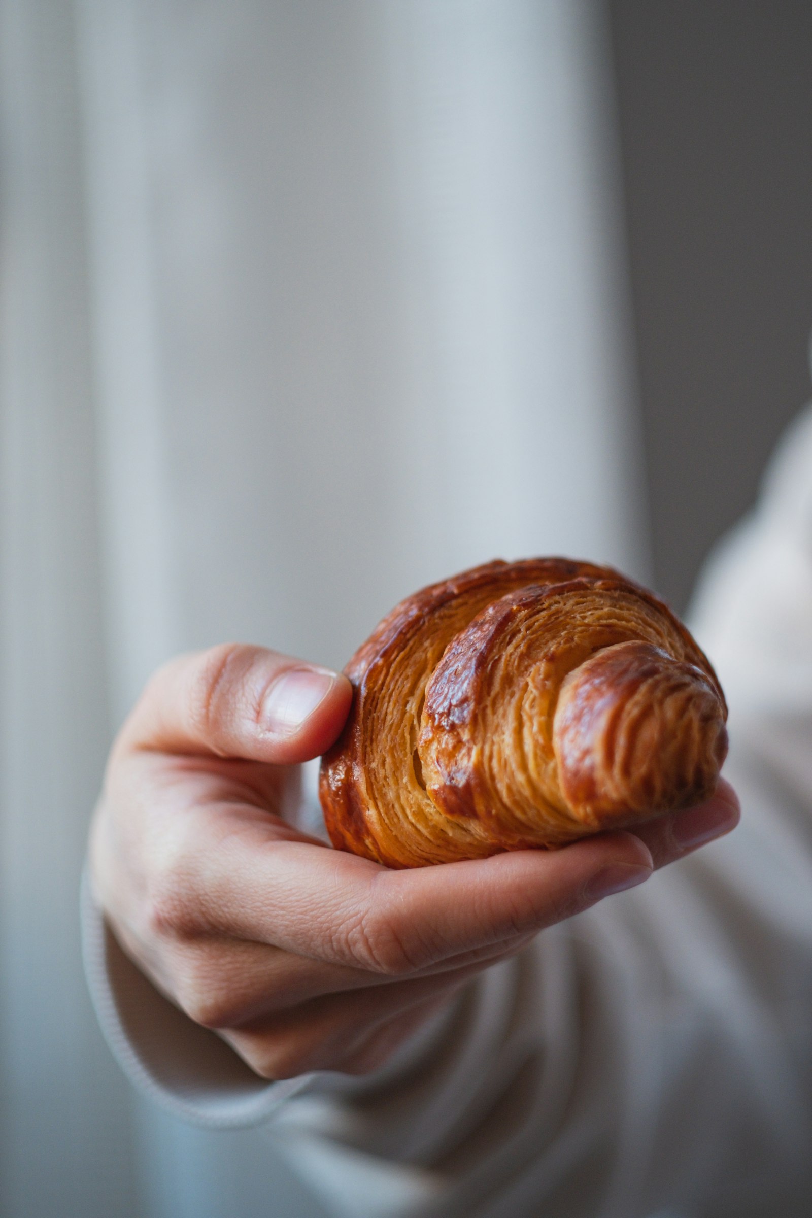 Manos sosteniendo un croissant recién hecho — experiencia de pastelería y programa de fidelización