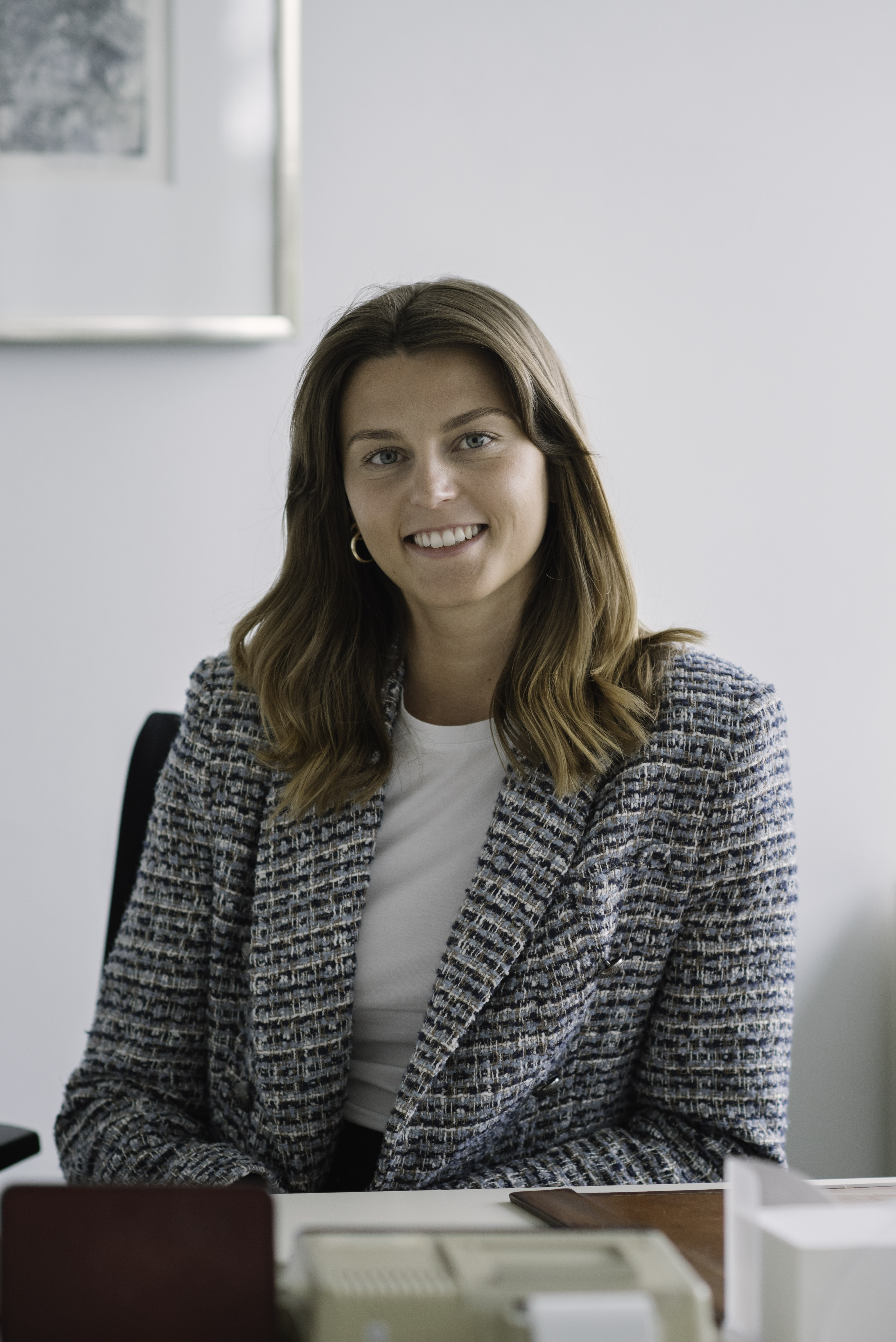 Professional portrait of a Scheyer team member seated at a desk, smiling confidently at the camera.