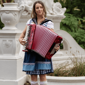 Lucy wearing a German outfit and playing her accordion