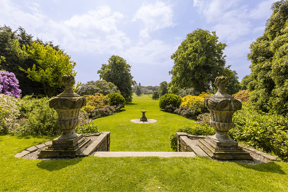 Formal English garden with stone urns and open parkland, representing orderly trust structures and long-term family planning in the United Kingdom.